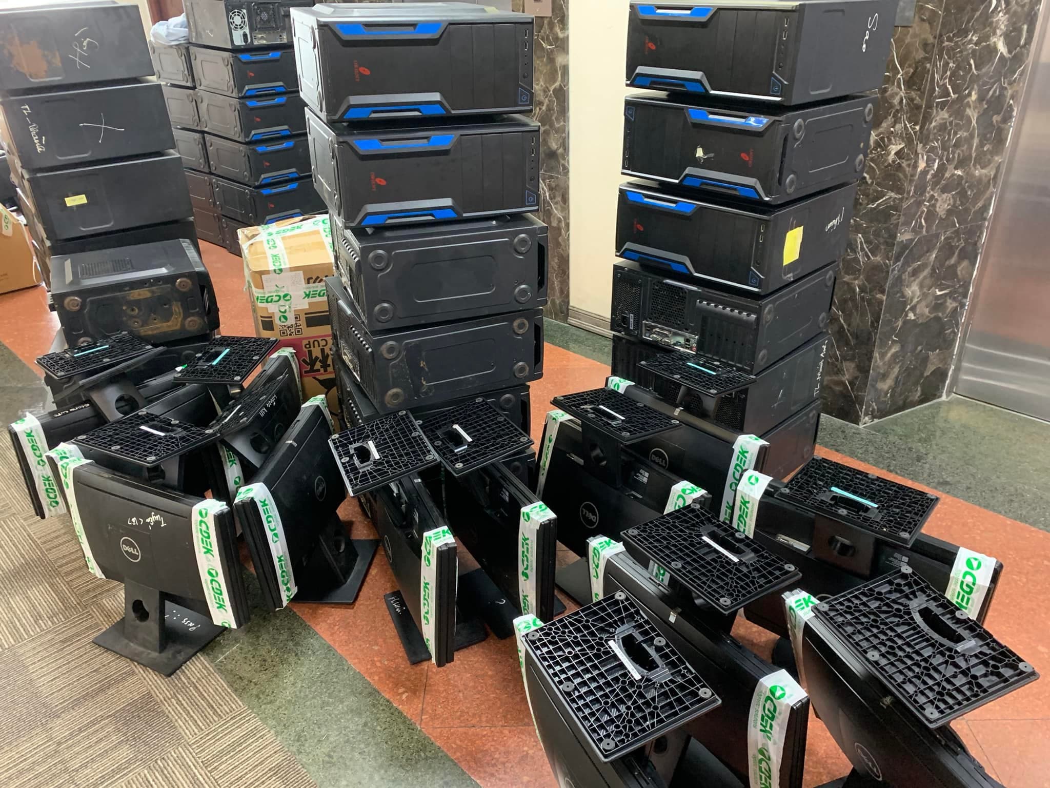 堆叠的黑色电脑主机和贴有绿色胶带的戴尔显示器摆放在室内地板上。