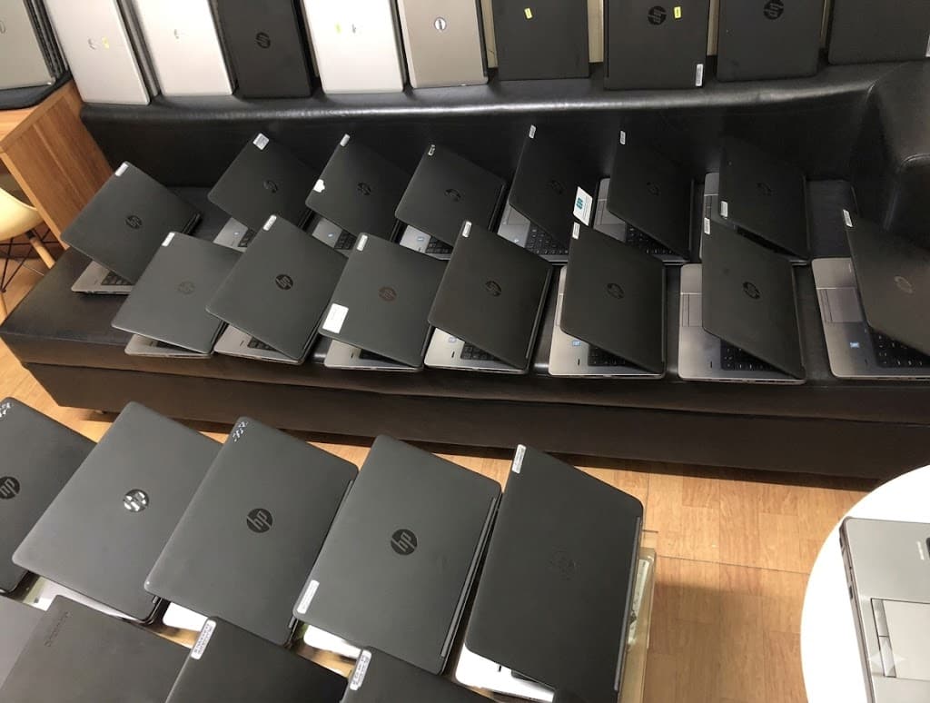 黑色长椅和桌面上整齐摆放着多排惠普品牌笔记本电脑。